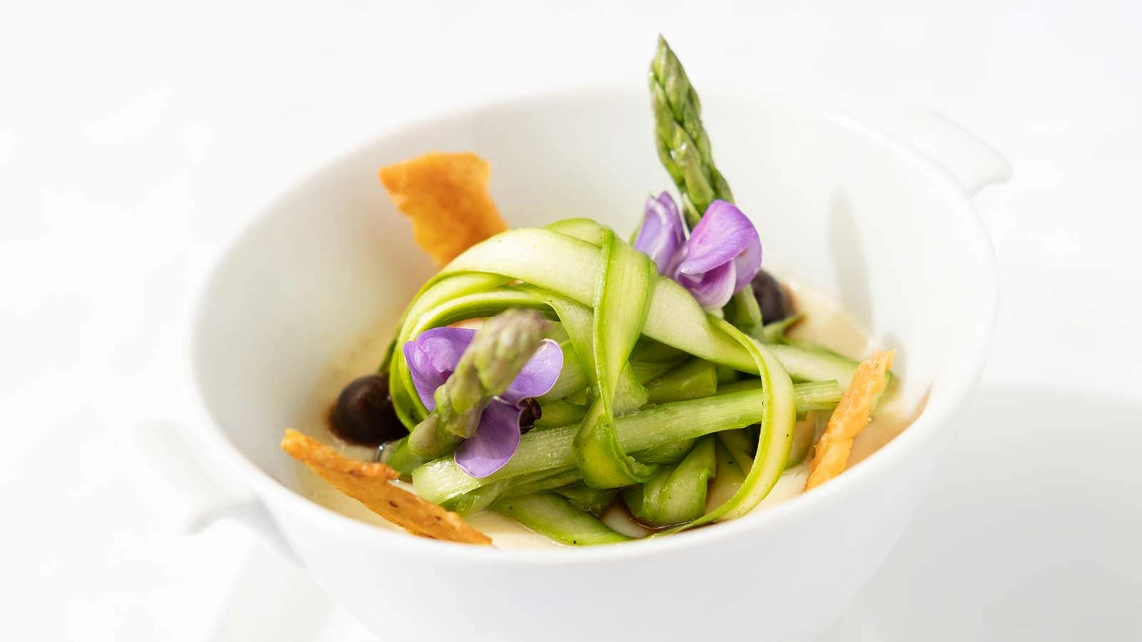 An asparagus salad tops a savory egg custard with chicken confit, mushrooms, and black garlic, served at Gatehouse Restaurant at the CIA at Greystone in St. Helena, CA.